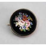 A gold mounted, round micro mosaic brooch, depicting a group of flowers.