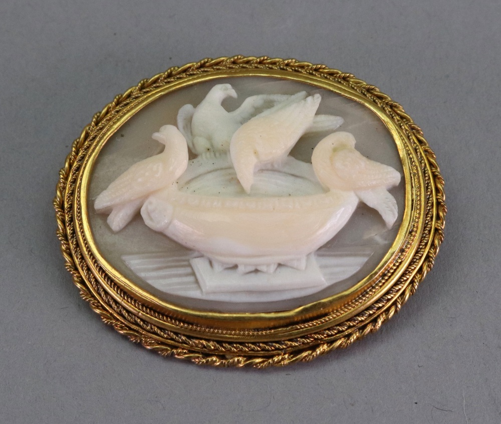 A Victorian gold mounted shell cameo brooch, carved as Pliny's doves drinking from a bowl,