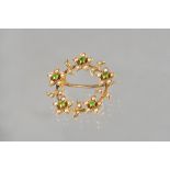 A gold, demantoid garnet and seed pearl set brooch, in a circular design, with five flowerheads,