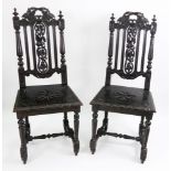 A pair of Victorian heavily carved ebonised oak hall chairs.