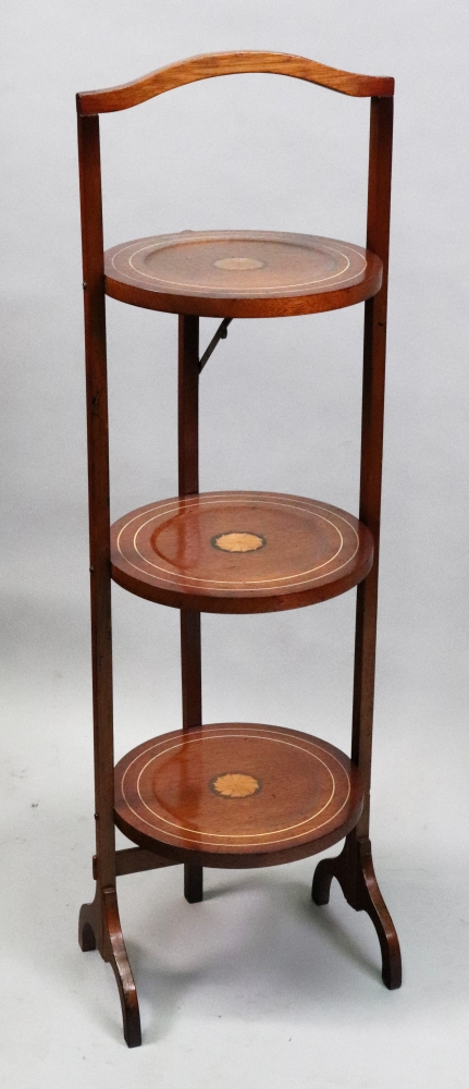 An Edwardian mahogany boxwood strung and paterae inlaid three tier folding cake stand, 90cm high.