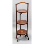 An Edwardian mahogany boxwood strung and paterae inlaid three tier folding cake stand, 90cm high.