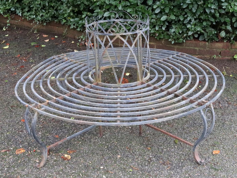 A grey wrought metal tree seat, 20th century, 144cm diameter.