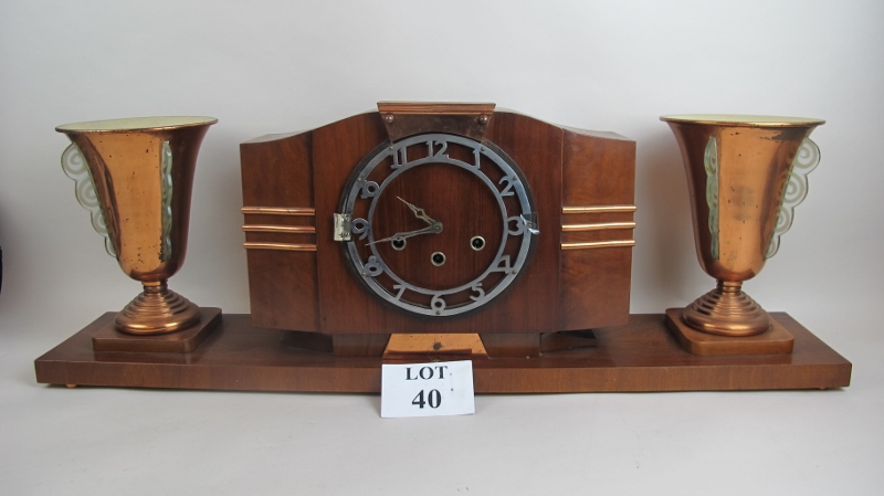 A French Art Deco walnut, chrome and copper mantel clock flanked by twin lamps, plinth base,