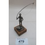 A silver figure on a wooden base of a 'Fly fisherman',