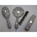 A four piece dressing table set with embossed flower and scroll decoration,