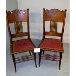 A pair of American oak framed hall chairs upholstered in studded red leather and with carved