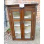 A 19th century oak corner cupboard with double glazed doors revealing three interior shaped shelves