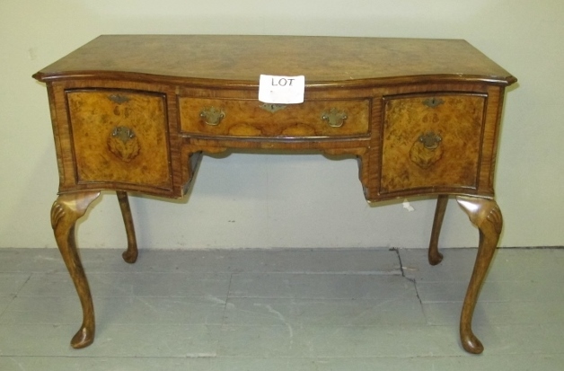 A c1920 Queen Anne design walnut desk with a centre drawer flanked either side by two deep drawers