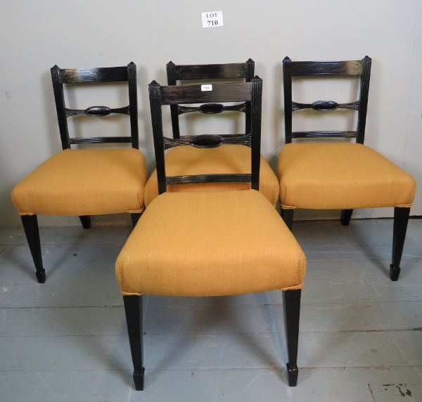 A set of four Edwardian black lacquered dining chair upholstered in gold material and terminating