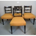 A set of four Edwardian black lacquered dining chair upholstered in gold material and terminating