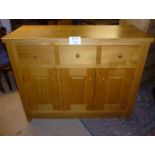 A large 20th century pine sideboard with three deep drawers to top over cupboard doors to base and