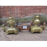 A pair of elaborate brass fire dogs modelled as urns with acorn finial's together with an iron fire