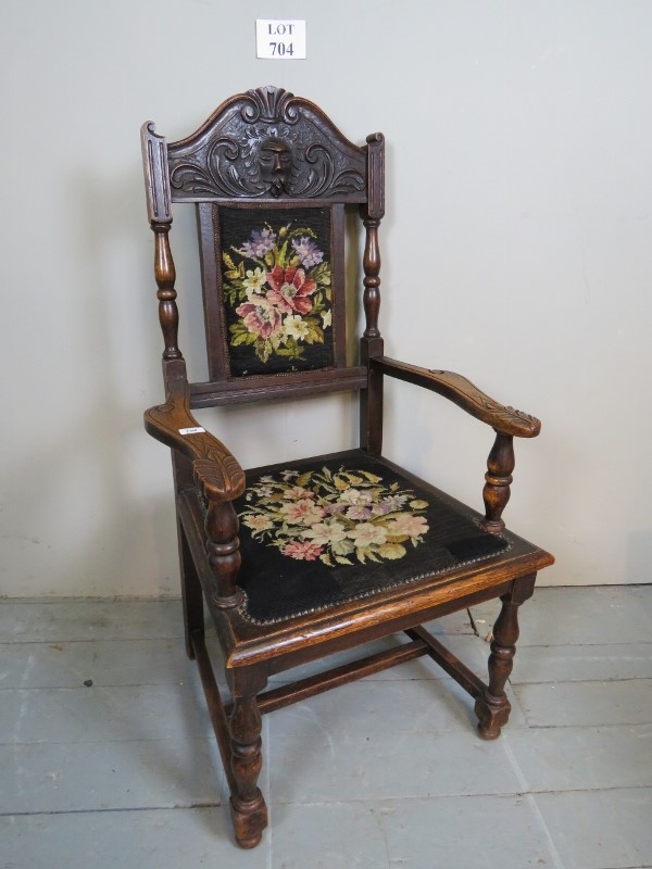 A Victorian carved oak framed armchair upholstered in floral tapestry and with turned supports