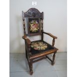 A Victorian carved oak framed armchair upholstered in floral tapestry and with turned supports