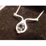 A sapphire and diamond pendant on a whit