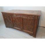 An 18th century oak coffer with carved panels to front and sides beneath a three plank top est: