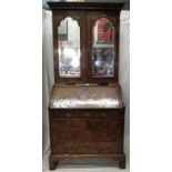 An early 18th century walnut bureau bookcase, with two mirrored doors,