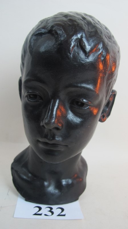 A bronze bust of a child's head, with pa