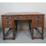 An early 20th century carved oak writing desk, with an inset tan leather,