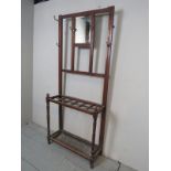 An Edwardian mahogany hall-stand with a central mirror, coat-hooks and umbrella stand,