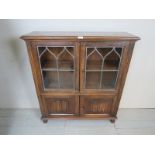 A 20th century old charm oak bookcase/cupboard with two glazed doors over cupboards to base,
