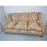 An Edwardian three seater sofa, upholstered in floral material,