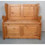 A small 20th century pine panel back settle, with a lift up seat, revealing internal storage area,