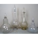 Four decorative assorted glass chemist bottles each complete with glass stoppers, smallest 19" high,