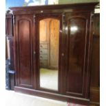 A late Victorian mahogany triple wardrobe with central mirror revealing linen slides over four