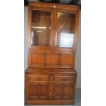 A C1960's Ercol Golden Dorm bookcase with double glazed doors to top over a fall front cupboard and