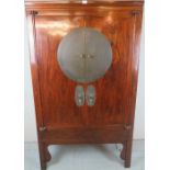 A 20th Century Chinese hardwood two door cupboard with brass plates to front and with a fitted