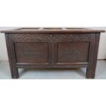 An 18th Century oak coffer with a panelled top over a carved frieze and two carved panels to front