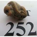 A Japanese fruitwood netsuke, signed, in the form of a monkey with applied cabochon eyes,