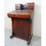 An Edwardian davenport desk with an inset leather slope beneath small drawers and with a cupboard