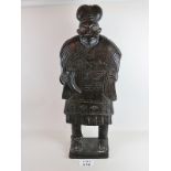 A large carved tribal statue of a man in decorative robes with horn cup,