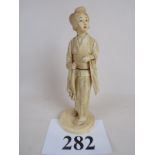 A Japanese Meiji period carved ivory okimono, signed, depicting a Geisha girl, 19 cm high,