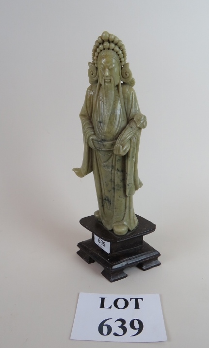 A carved Chinese figure of an elder in soapstone, on a wooden base,