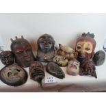 A collection of twelve tribal masks from various regions and various styles, most carved from wood,