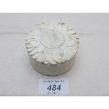 A circular ivory box with carved flower