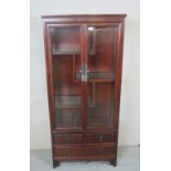 A 20th Century hardwood Chinese glazed cabinet with fixed shelves over drawers est: £100-£200