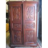 A continental carved oak armoire with double panelled doors revealing internal hanging area (no