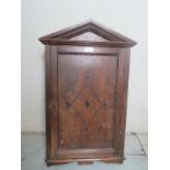 A small 19th Century oak wall hanging cabinet with an arched top over a single door revealing an