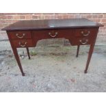 An Edwardian mahogany writing table with an inset black leather top, over a long central drawer,