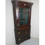 An 18th Century oak corner cabinet with a glazed cupboard to top over a single panelled door to