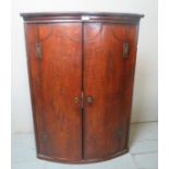 A 19th Century oak bow front corner cabinet with double doors revealing internal shaped shelves