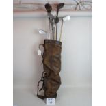 A vintage leather golf bag and clubs,