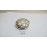 A silver embossed circular box,