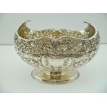 AN EDWARDIAN SILVER BOAT FORM DISH, having pierced rim and embossed body, on oval platform foot,