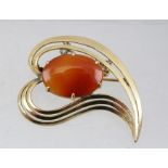 A 14K GOLD BROOCH SET WITH LARGE OVAL STONE in a sweeping heart frame, with safety chain